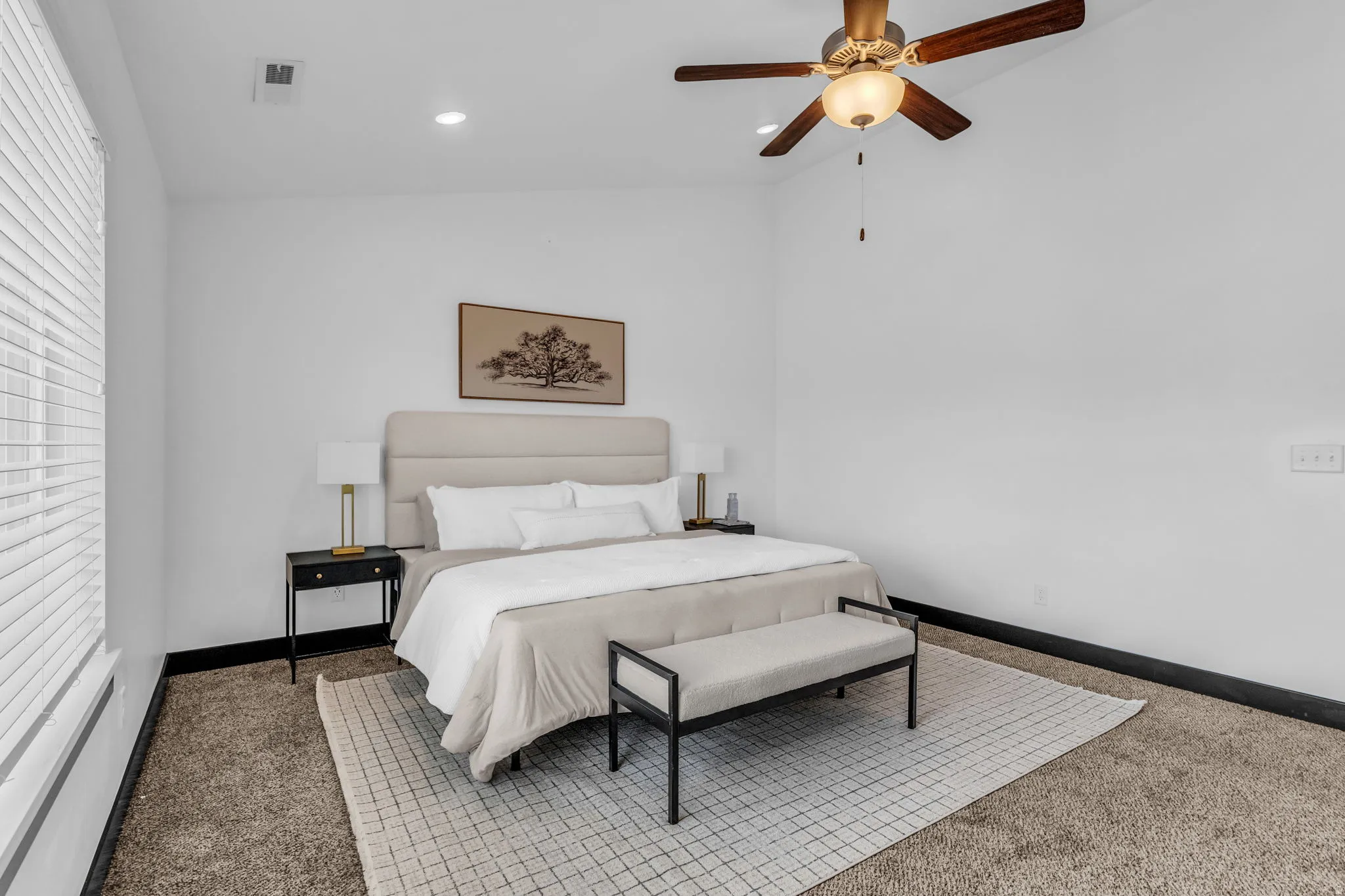 Spacious room featuring neutral carpeting, a large window with blinds, recessed lighting, a ceiling fan with light fixture, and dark baseboards