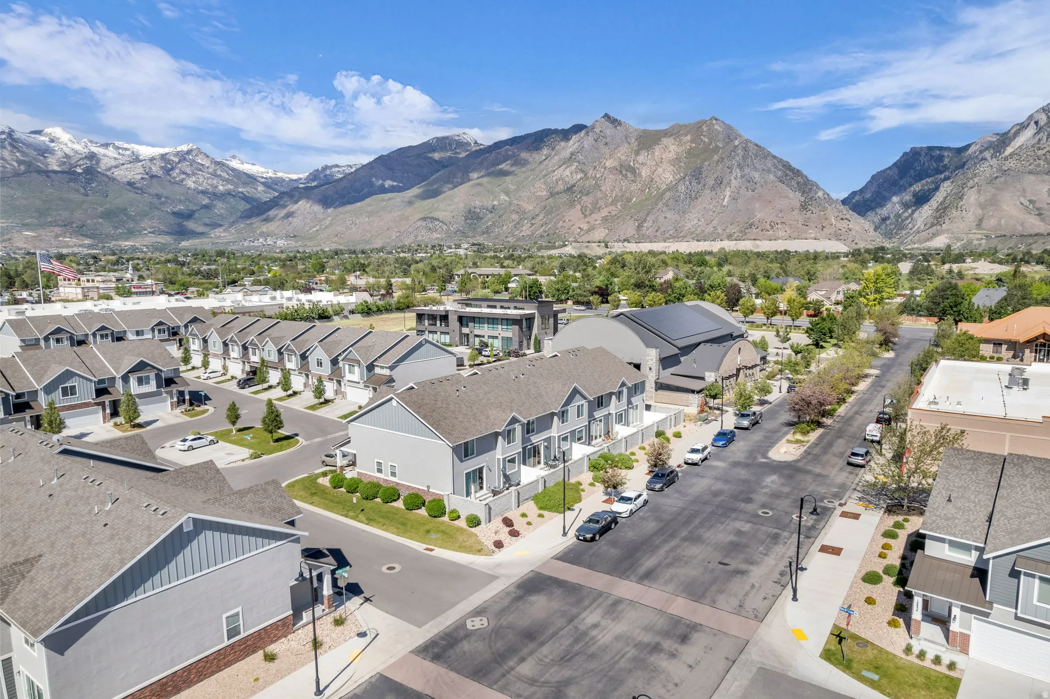Modern residential community featuring multi-story townhomes with light gray siding and dark shingle roofs
