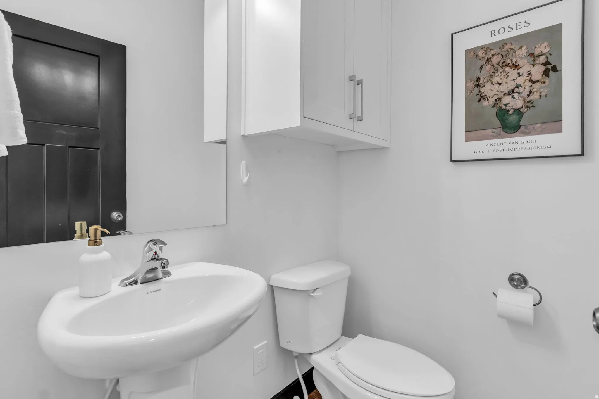 Pedestal sink with chrome faucet, white toilet, and upper cabinetry