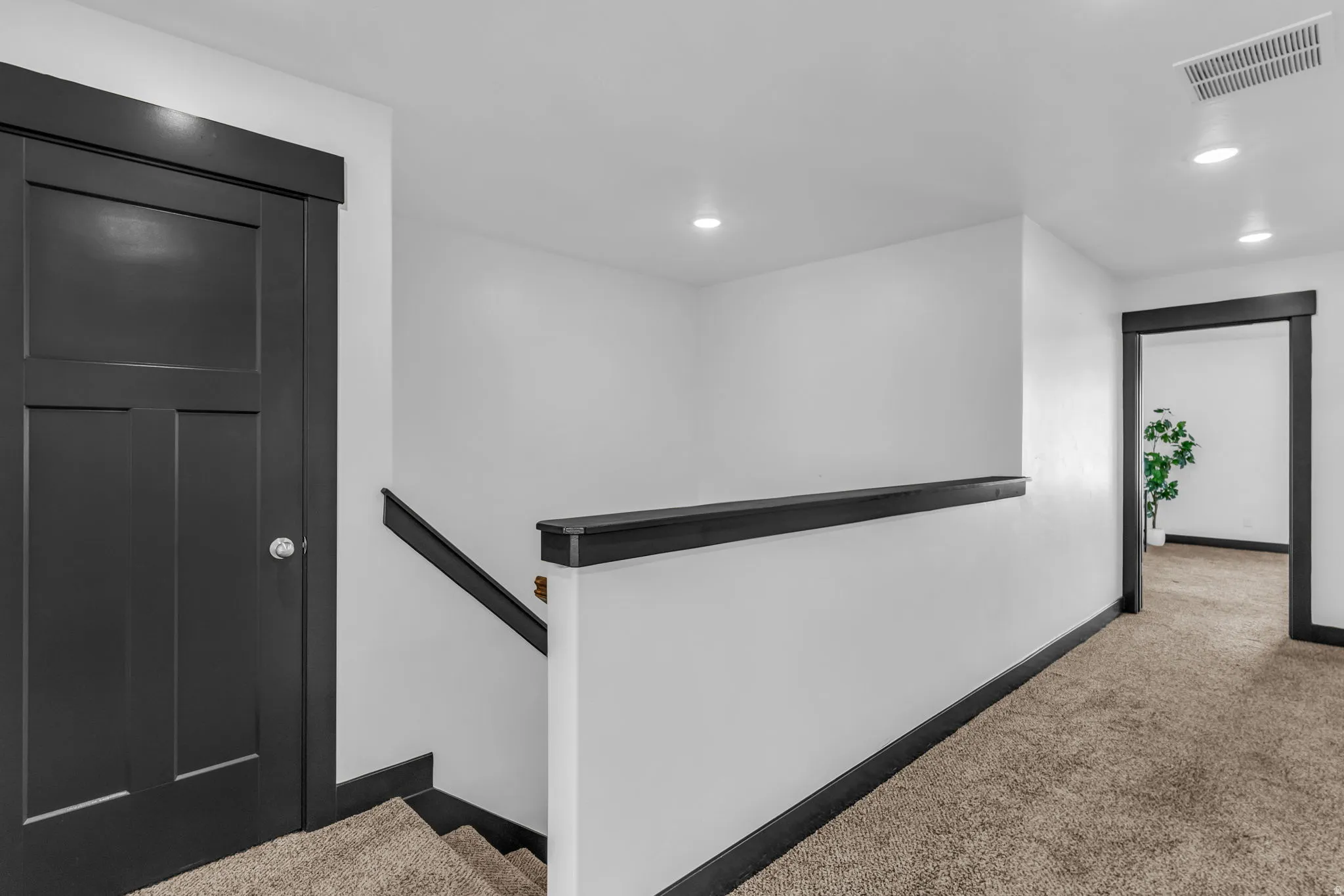 Upper landing featuring neutral carpeting and a white wall with dark trim