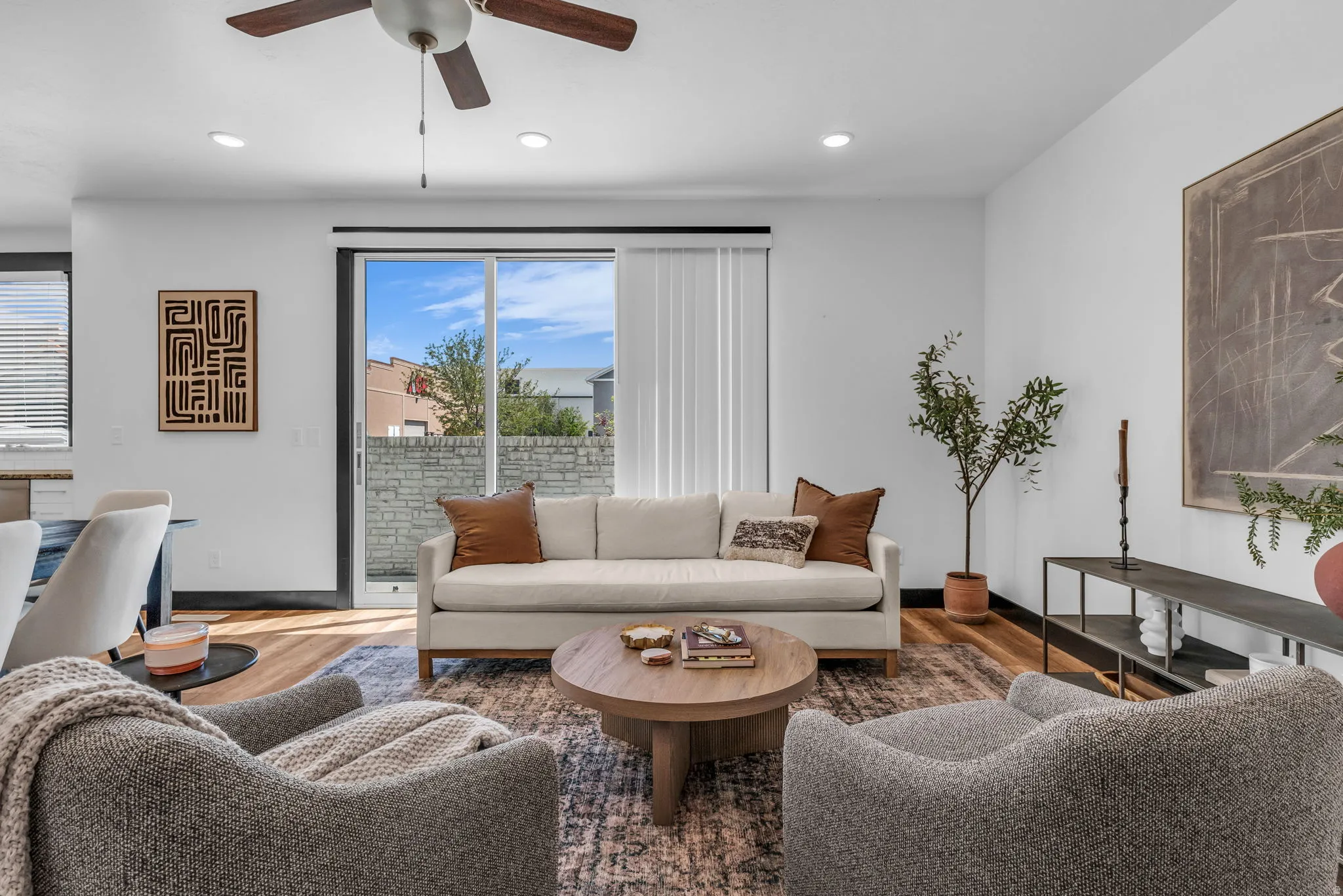 Living area featuring wood-finish flooring and a ceiling fan with integrated lighting