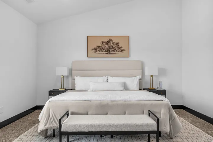 Vaulted ceiling over a neutral-toned room featuring light-colored walls and dark baseboards