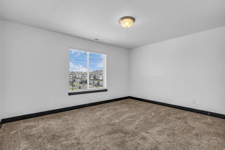 Carpeted interior space with a window featuring horizontal blinds