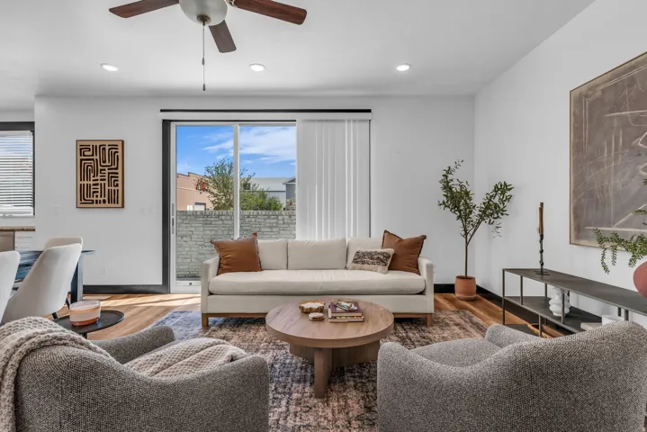 Living area featuring wood-finish flooring and a ceiling fan with integrated lighting