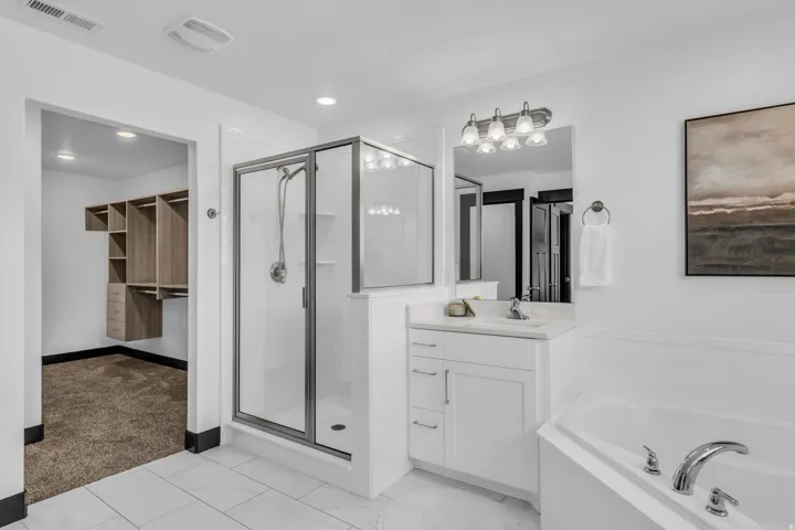 Bathroom featuring white tile flooring and a built-in corner tub with chrome fixtures