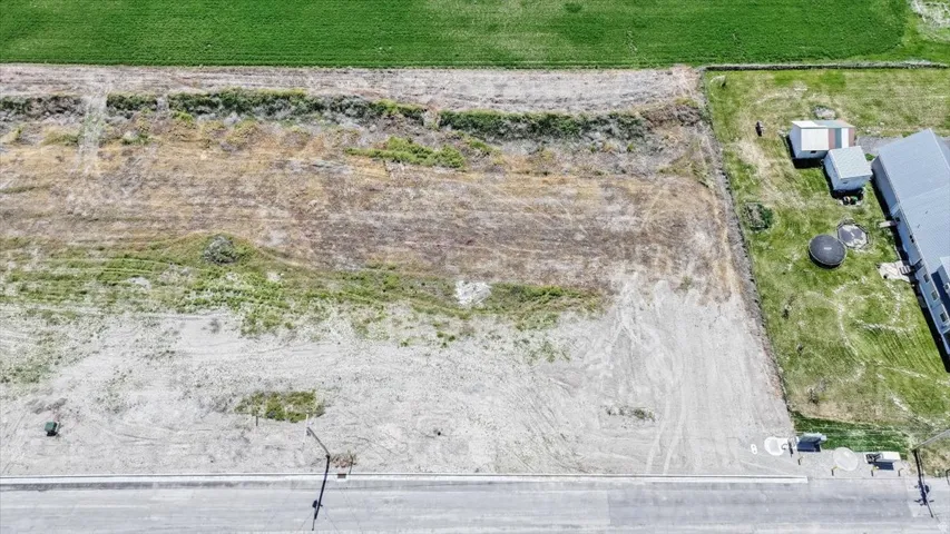 Expansive vacant lot featuring a paved roadway, curbside utilities, and a flat topography