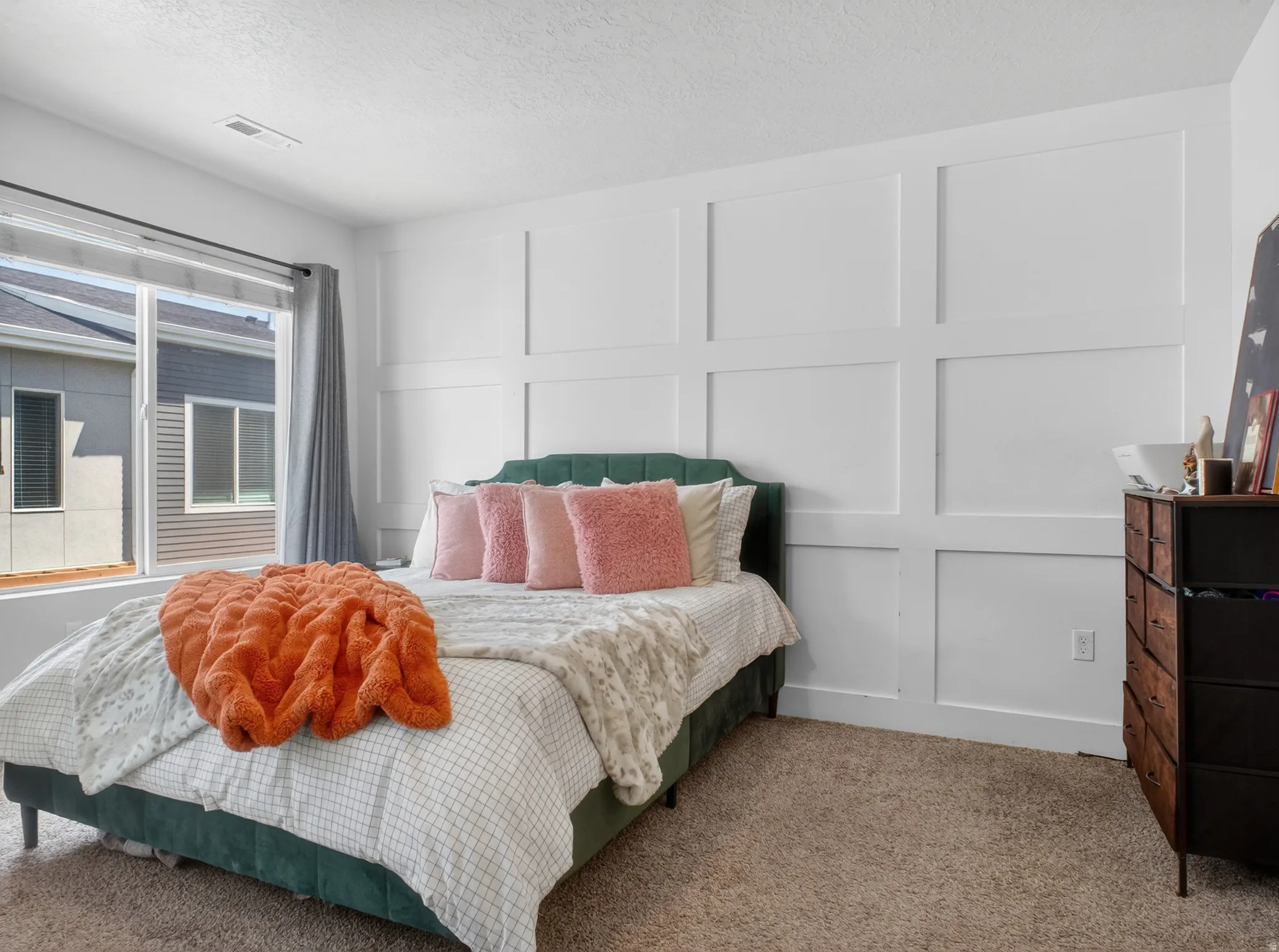 Bedroom with a large window, white board and batten accent wall, and neutral carpeting
