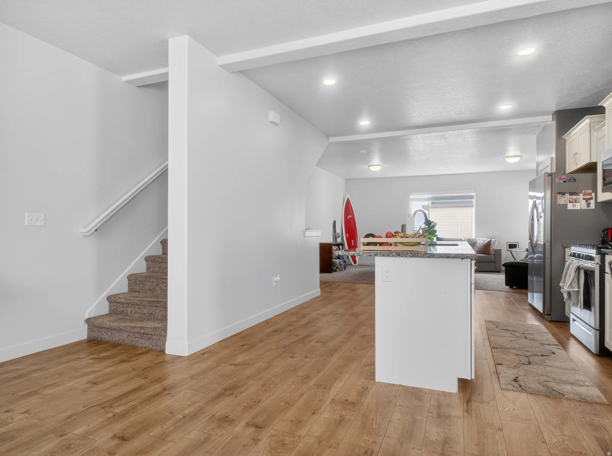 Open-concept living space with wood-finish flooring, a kitchen island with stone countertop, and recessed lighting