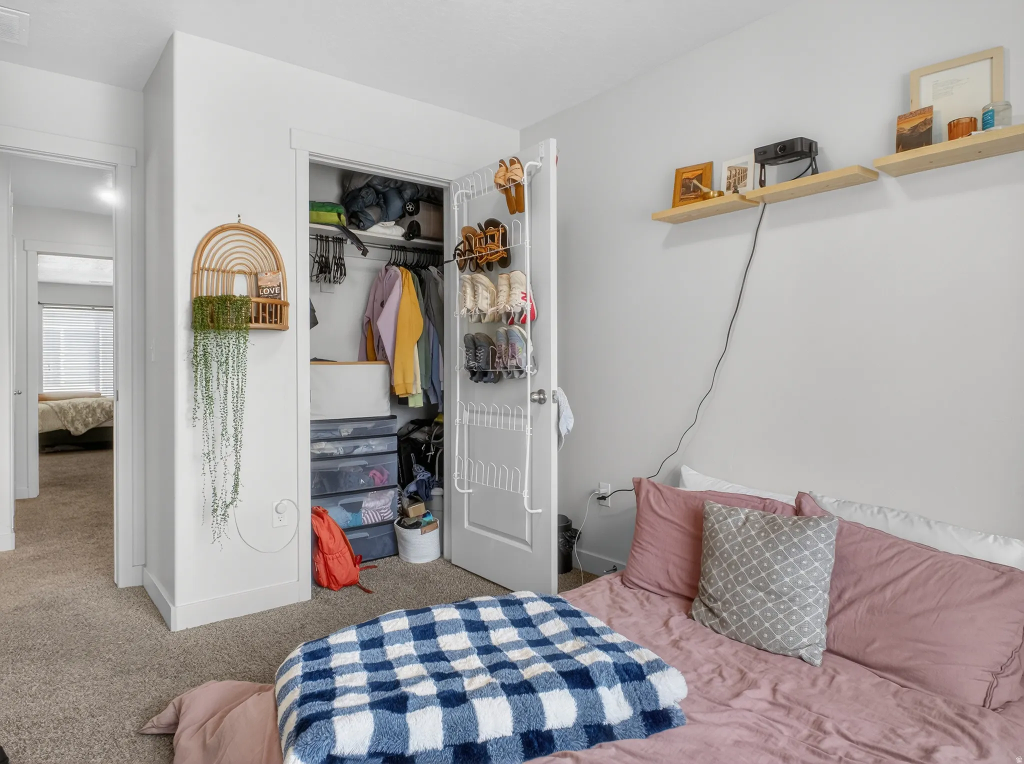 Carpeted bedroom featuring a closet with bi-fold doors, white baseboards, and built-in wall shelving
