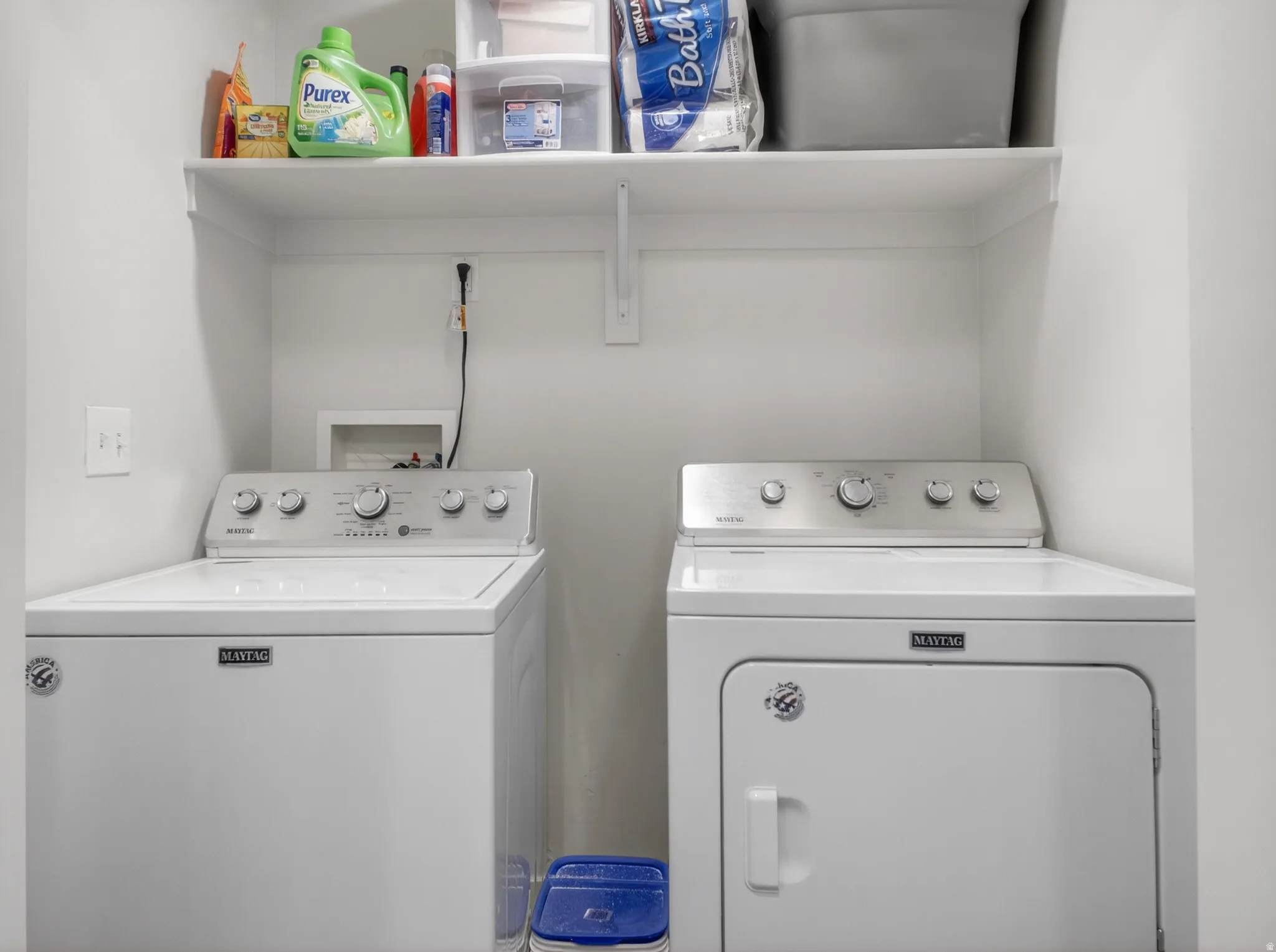 Dedicated laundry area featuring a white top-load washer and front-load dryer set, along with a built-in wall shelf