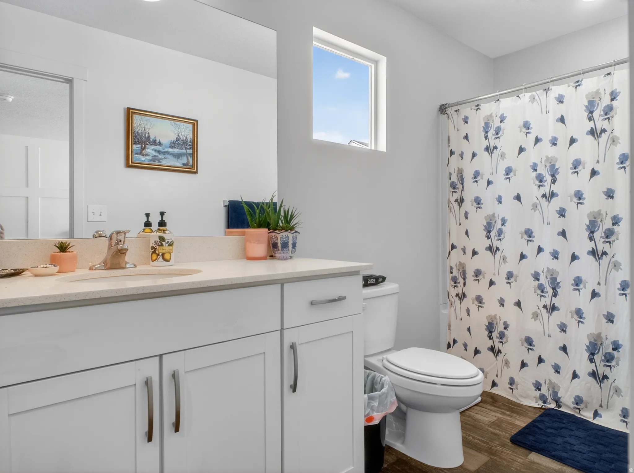 Bathroom featuring a single vanity with an integrated sink, light-toned countertop, and white cabinetry with brushed nickel hardware