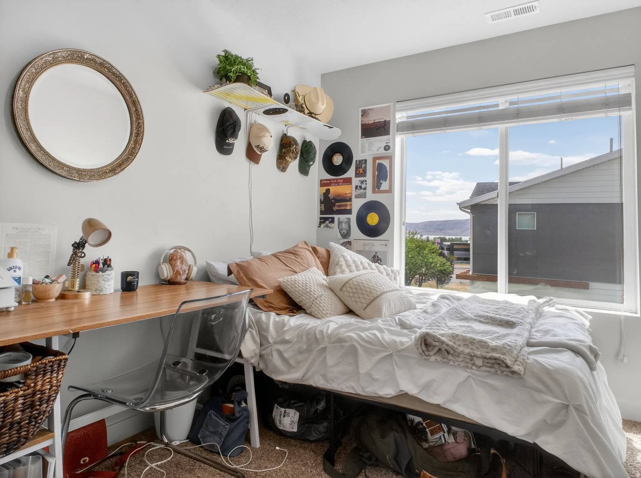Bedroom featuring a large window, a wood-finish desk, and a textured wall mirror