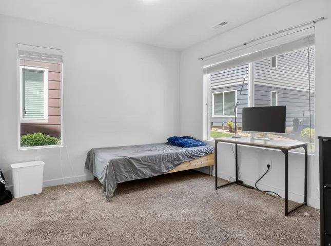 Carpeted room featuring two windows with blinds, providing natural illumination