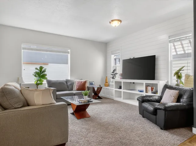 Living area featuring a shiplap accent wall with built-in shelving, recessed lighting, and large windows