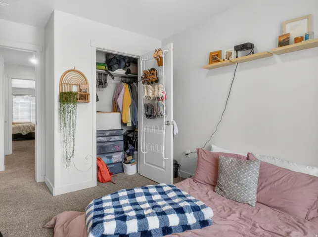 Carpeted bedroom featuring a closet with bi-fold doors, white baseboards, and built-in wall shelving