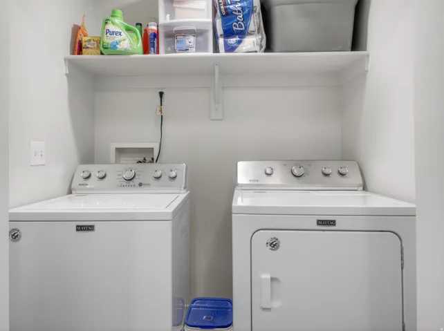 Dedicated laundry area featuring a white top-load washer and front-load dryer set, along with a built-in wall shelf