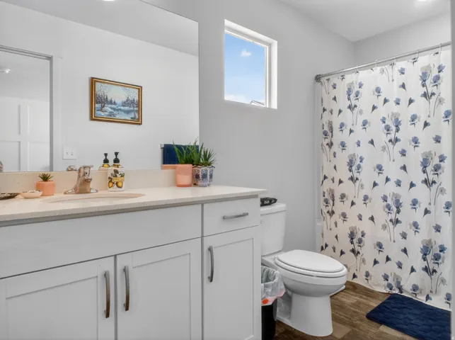 Bathroom featuring a single vanity with an integrated sink, light-toned countertop, and white cabinetry with brushed nickel hardware