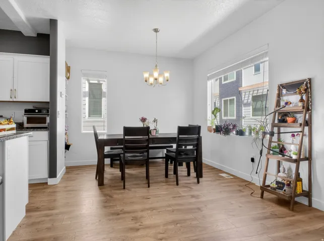 Open-concept dining area featuring wood-finish flooring, white walls, and a multi-light chandelier