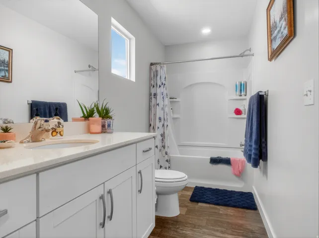 Bathroom featuring a single vanity with stone-look countertop, integrated sink, and white cabinetry