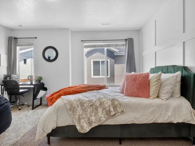 Spacious room featuring light-colored walls, carpet flooring, and multiple windows with curtain rods