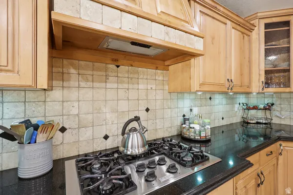 Stainless Steel Gas Cooktop with Hooded Vent - Tile Backsplash & Granite Countertops