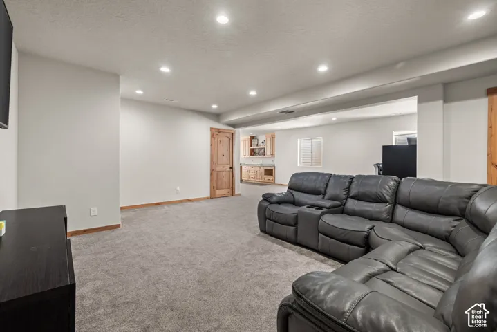 Spacious entertainment area with recessed lighting, light gray carpeting, and light-toned walls