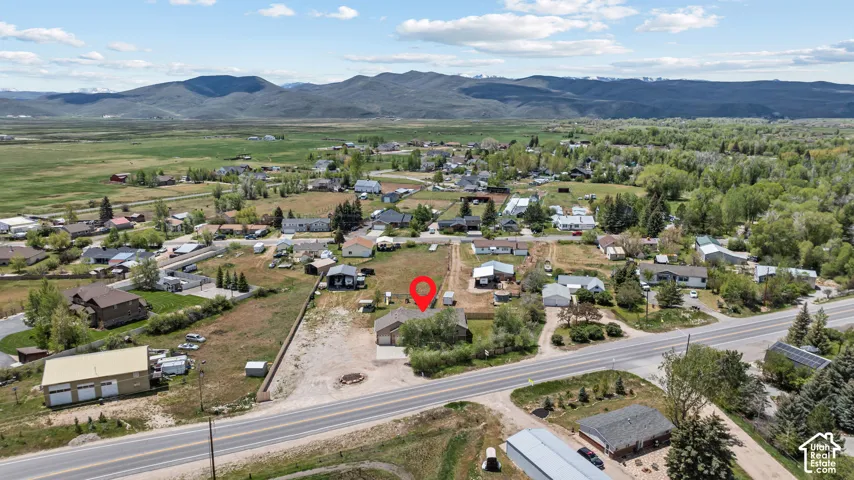Expansive lot with a single-story residence and detached garage, featuring a paved driveway and surrounding natural landscape