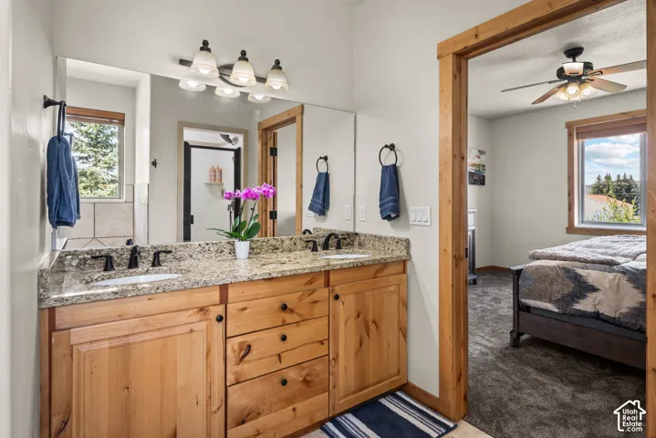 Bathroom vanity featuring dual sinks, granite countertop, and wood cabinetry