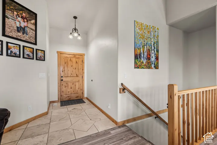 Entryway featuring a natural wood door with dark hardware, a three-light chandelier, and light-toned tile flooring