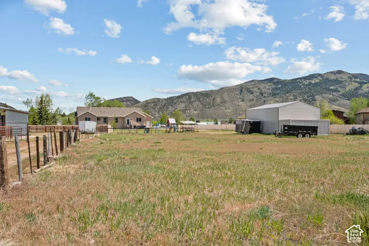 Expansive grassy yard with a wooden fence and mountain backdrop