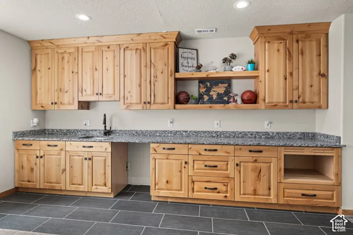 Extensive built-in cabinetry with natural wood-finish, featuring a black countertop with an integrated sink and black faucet
