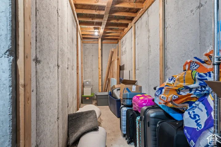 Unfinished basement area featuring exposed wood framing, concrete foundation walls, and overhead lighting