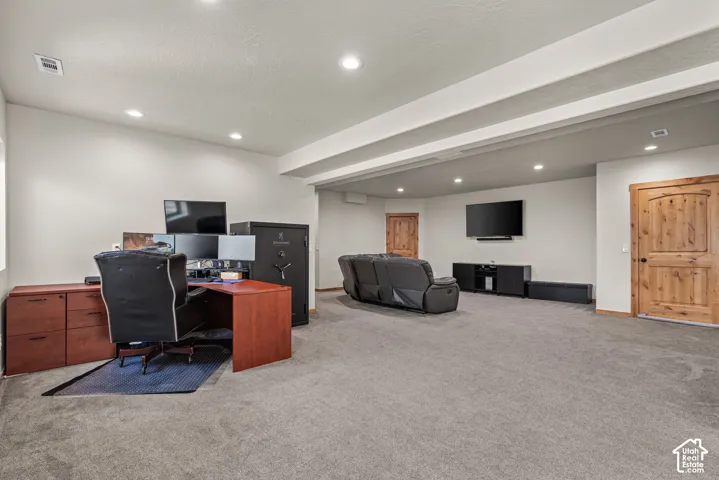 Spacious room featuring gray carpeting, recessed ceiling lighting, and light wood-grain doors