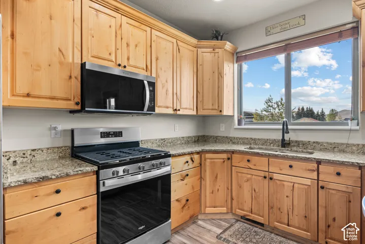 L-shaped kitchen with light wood cabinetry, granite countertops, and wood-finish flooring