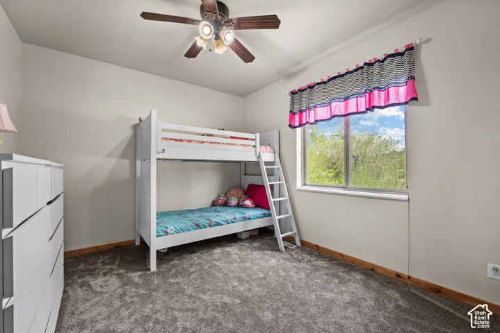 Bedroom featuring gray carpet flooring, light neutral wall paint, and a window offering natural light