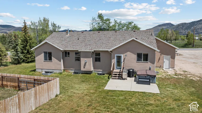 Rear exterior of a stucco residence featuring a shingle roof