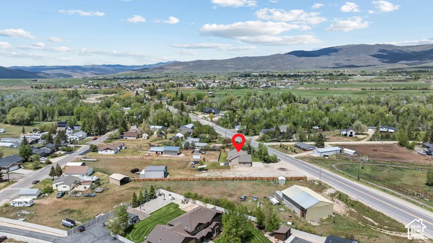 Aerial perspective showcasing the property's position within a residential area, surrounded by expansive green landscapes and distant mountains