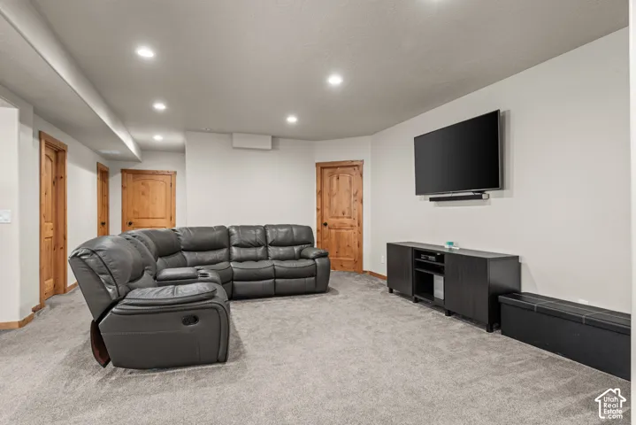 Recessed lighting illuminates a spacious room featuring light gray carpeting and white walls