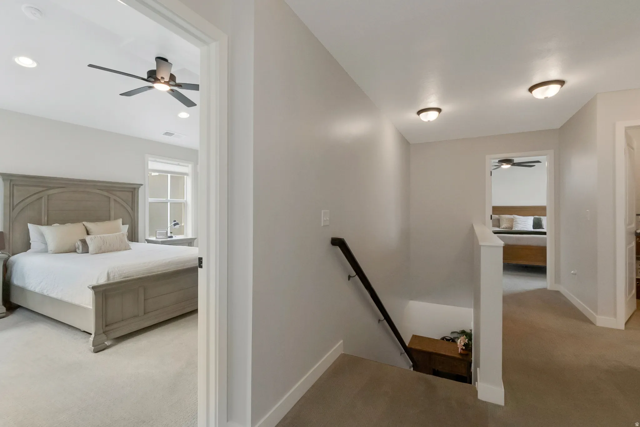 Carpeted hallway featuring a dark wood handrail, white trim, and ceiling-mounted light fixtures