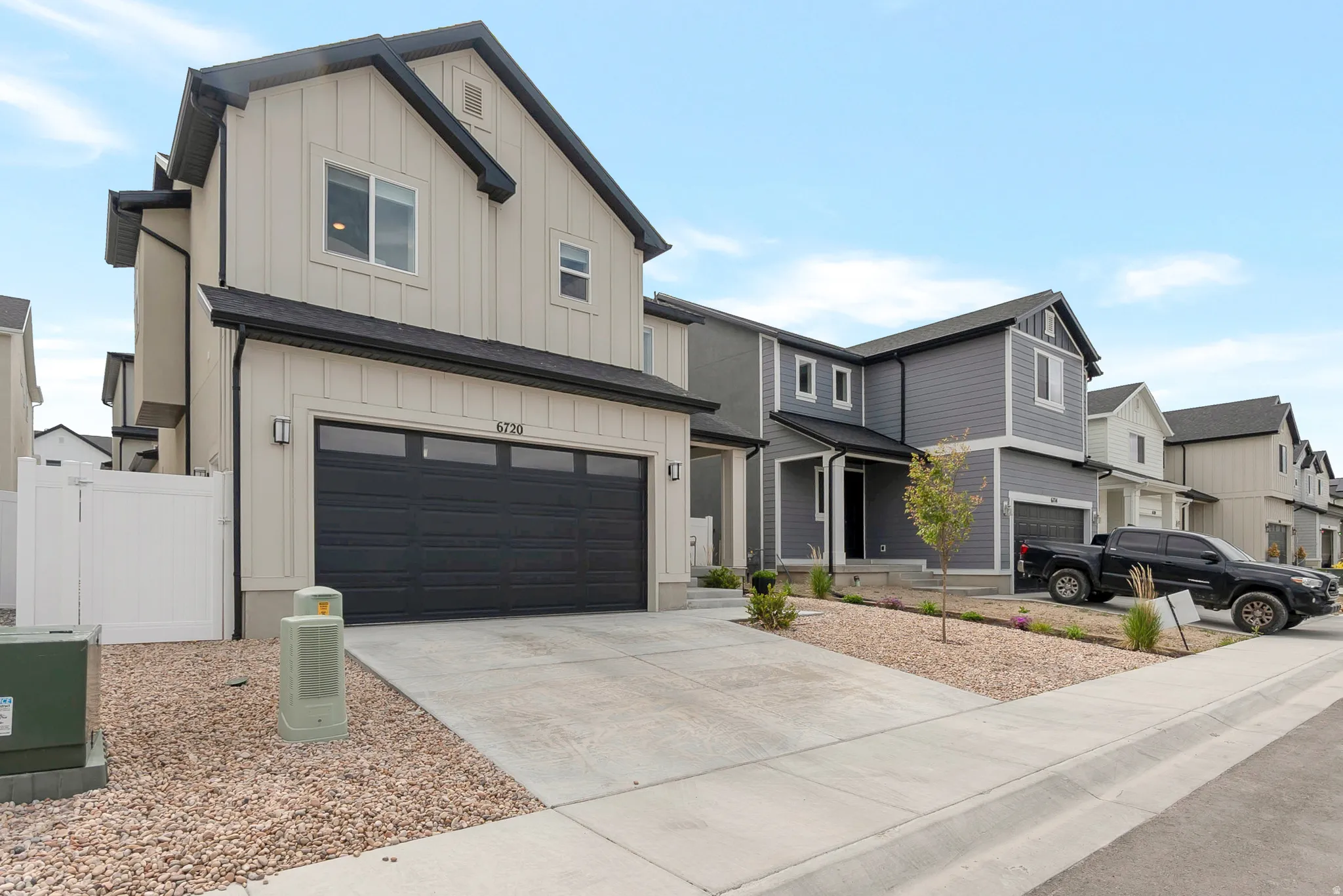 Contemporary two-story residence with board and batten siding, a dark roofline, and a black garage door with horizontal windows