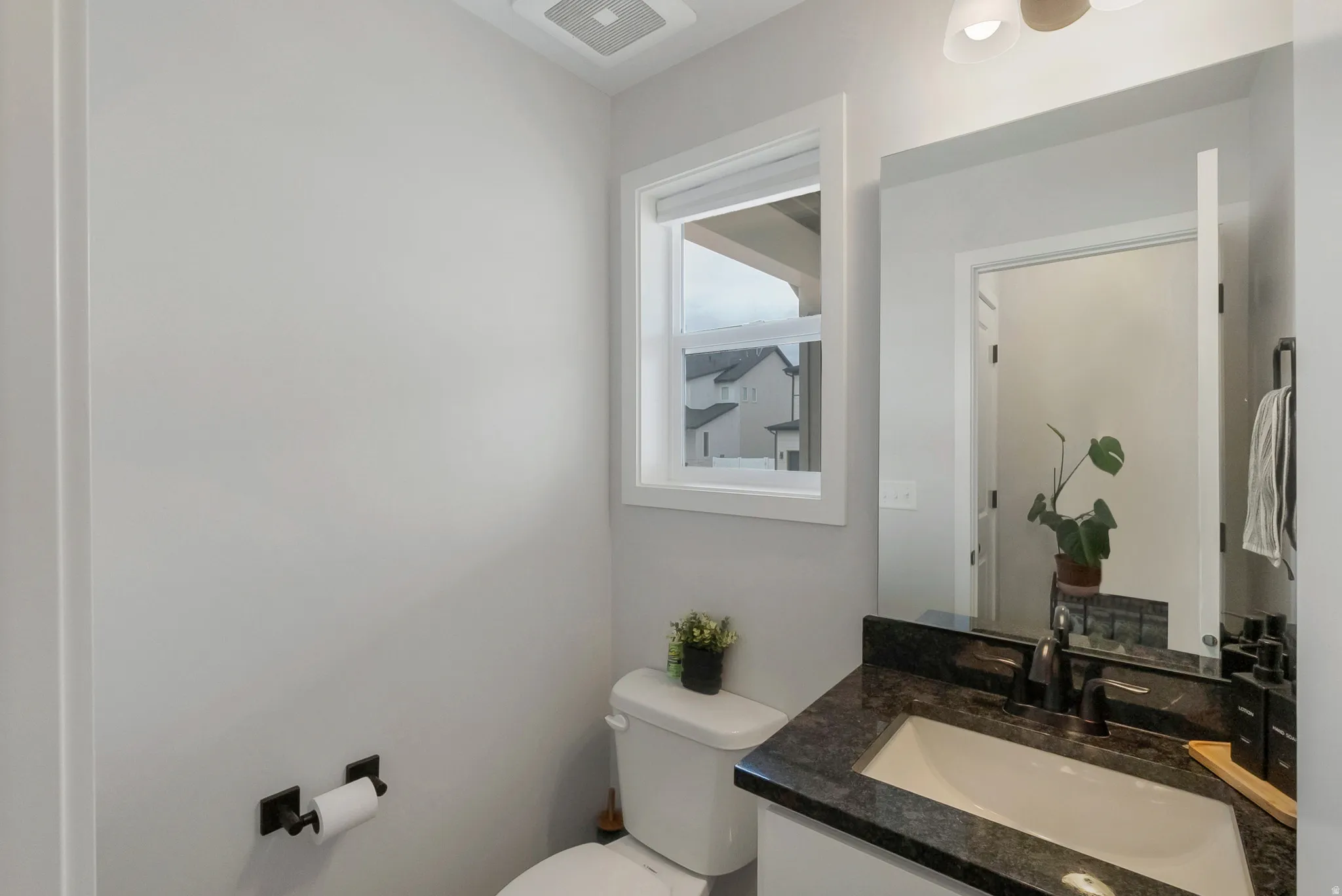 Bathroom vanity featuring a dark granite countertop and integrated white sink