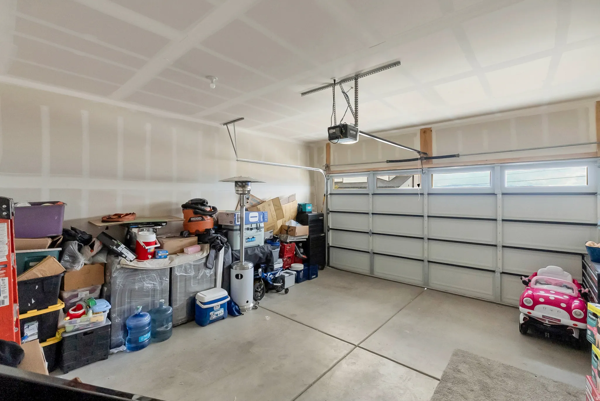 Two-car garage featuring a sectional garage door with upper windows, automatic opener, and concrete flooring