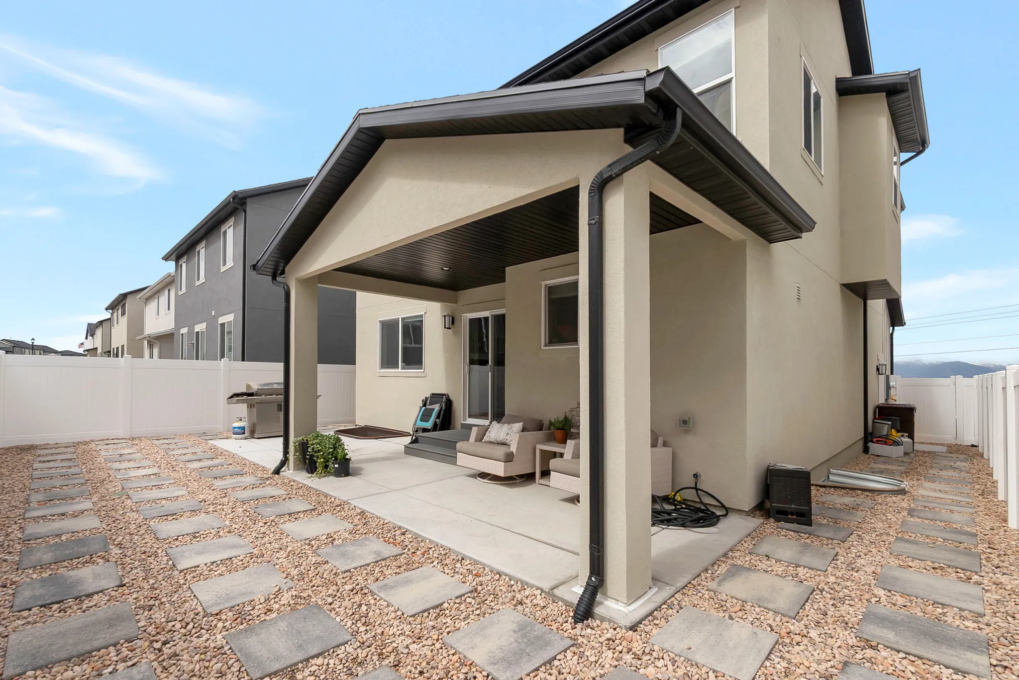 Covered patio with concrete flooring, stucco exterior, and dark trim