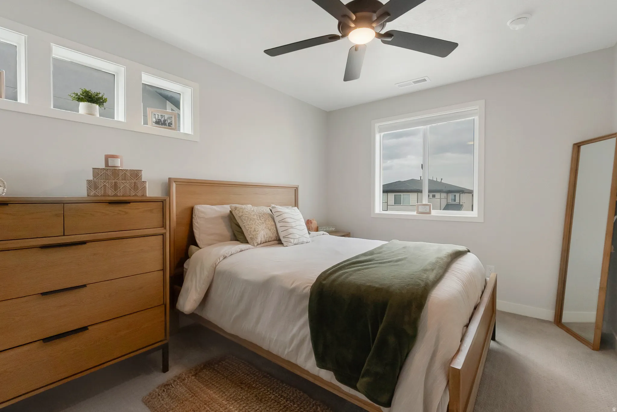 Bedroom featuring light gray walls, carpet flooring, a ceiling fan, and multiple windows
