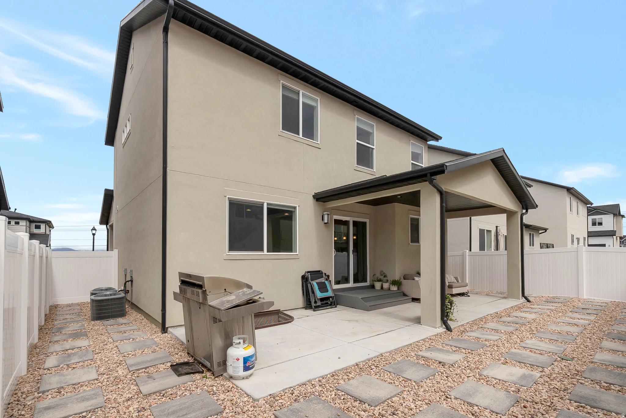 Rear exterior featuring a covered patio, sliding glass door, and multiple windows