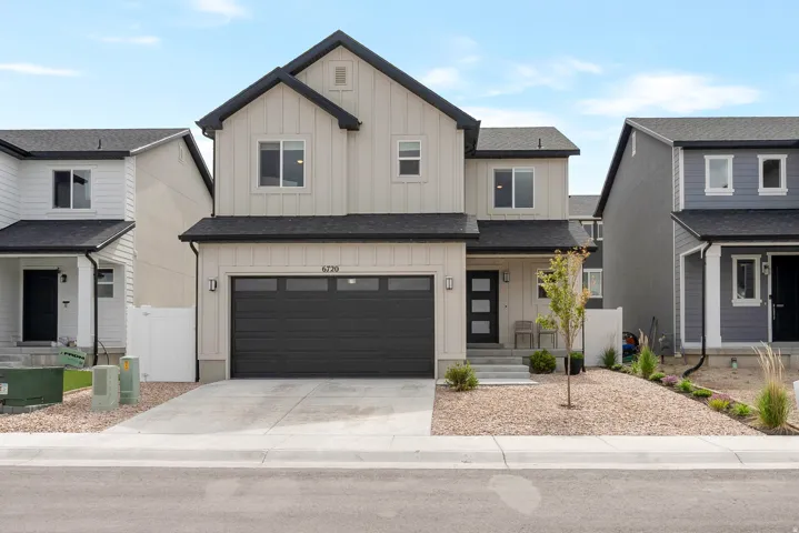 Two-story contemporary residence featuring a two-car garage with a dark sectional door, light vertical siding, and a dark shingle roof