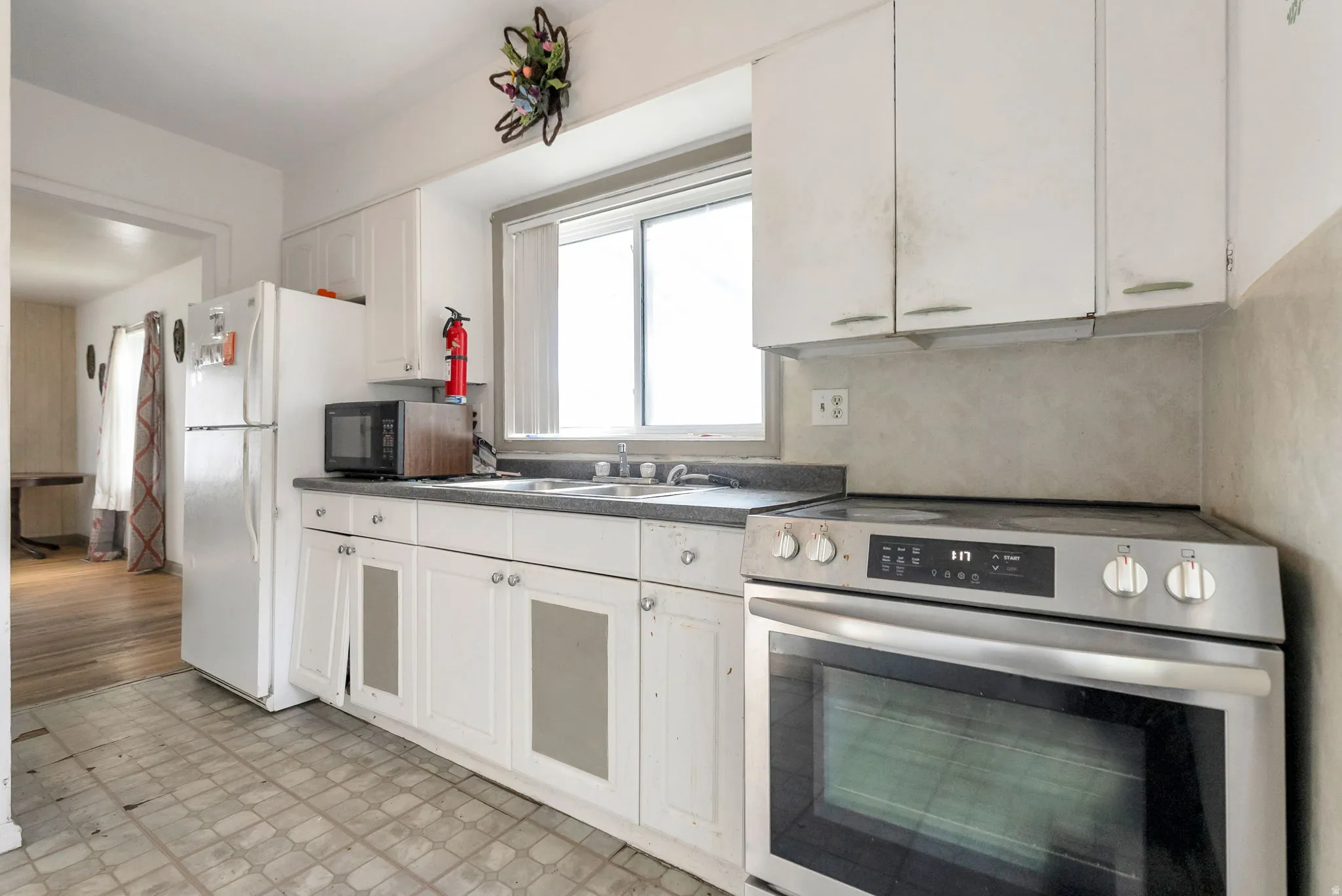 Kitchen featuring white cabinetry, a double basin stainless steel sink, dark countertops, and a modern stainless steel range