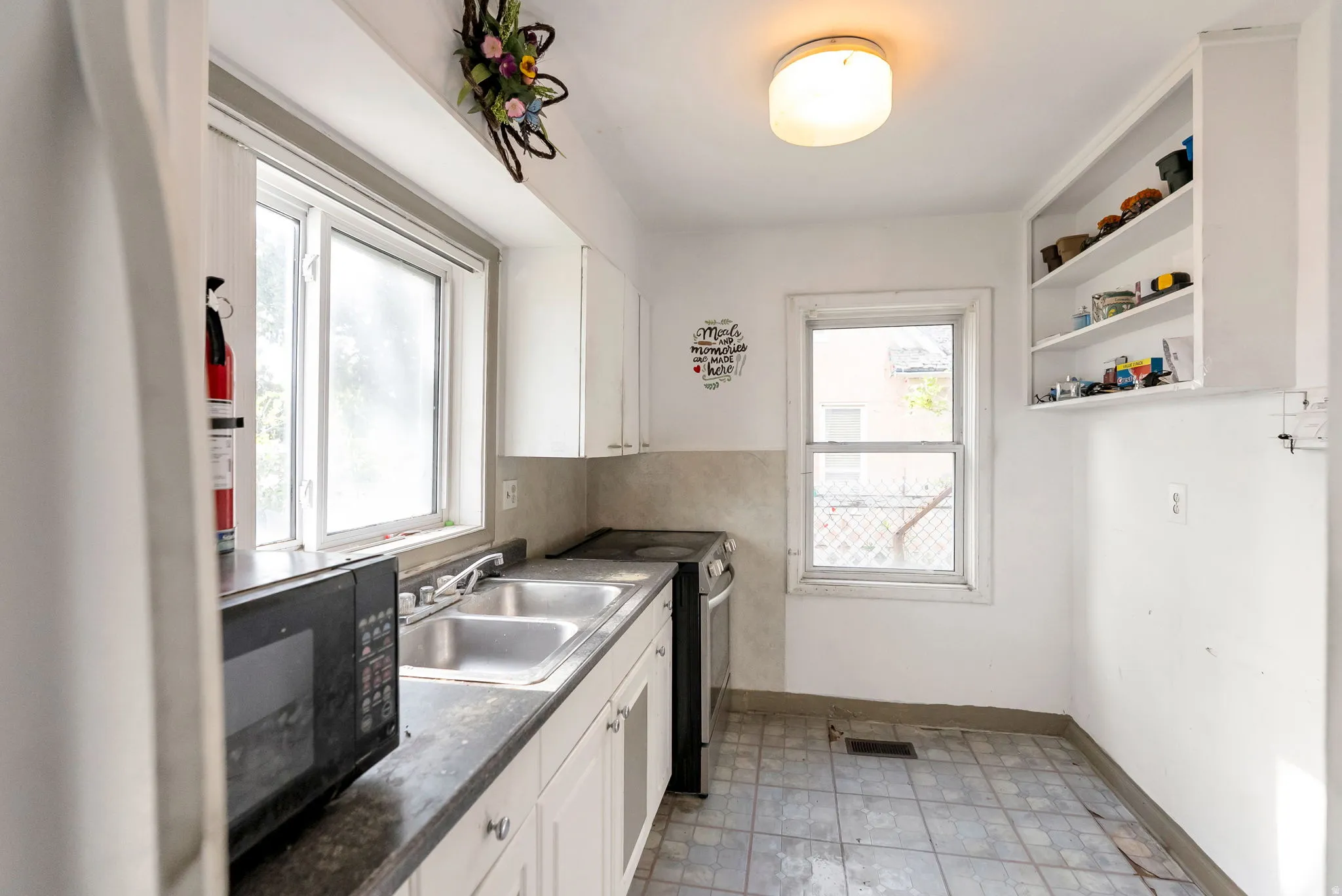 Kitchen featuring white cabinetry, a double basin stainless steel sink, dark countertops, and tile flooring