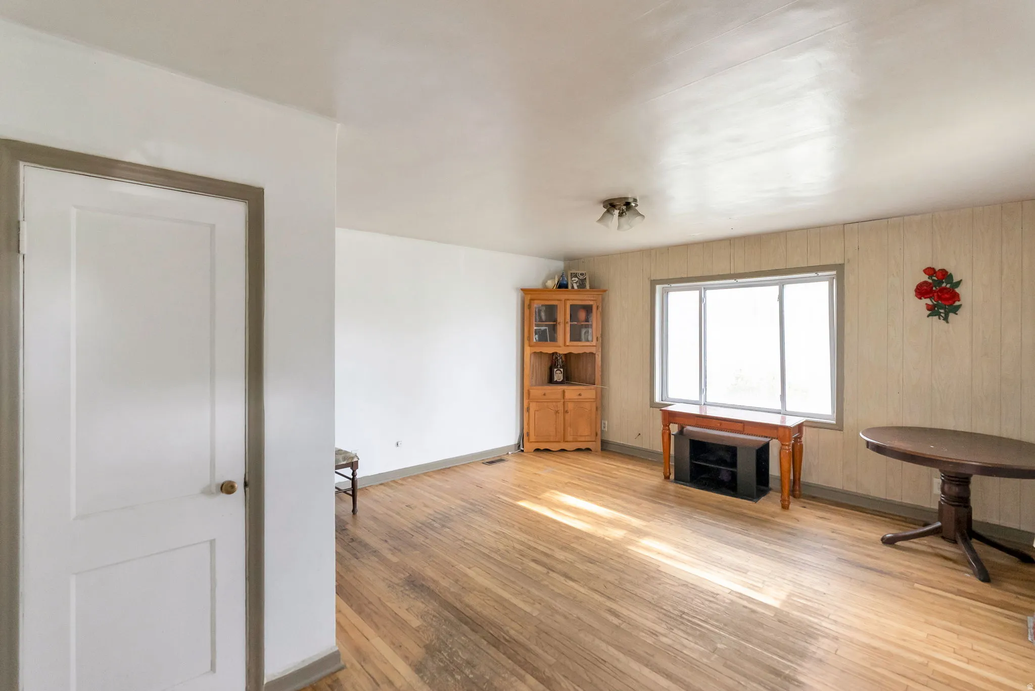 Hardwood flooring throughout the room, complemented by a large window with white trim