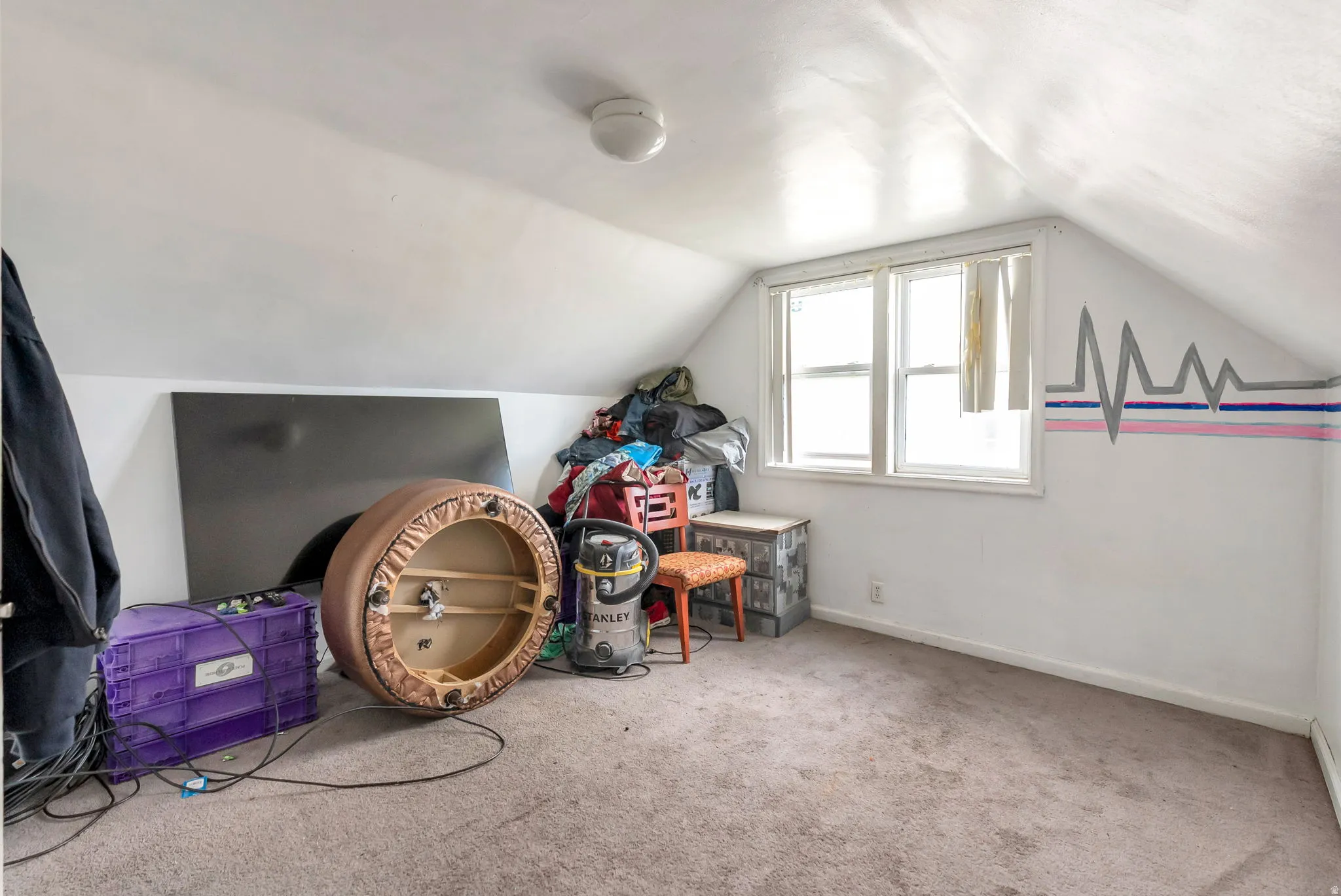 Carpeted attic space featuring sloped ceilings, a double window, and a flush-mount ceiling light fixture